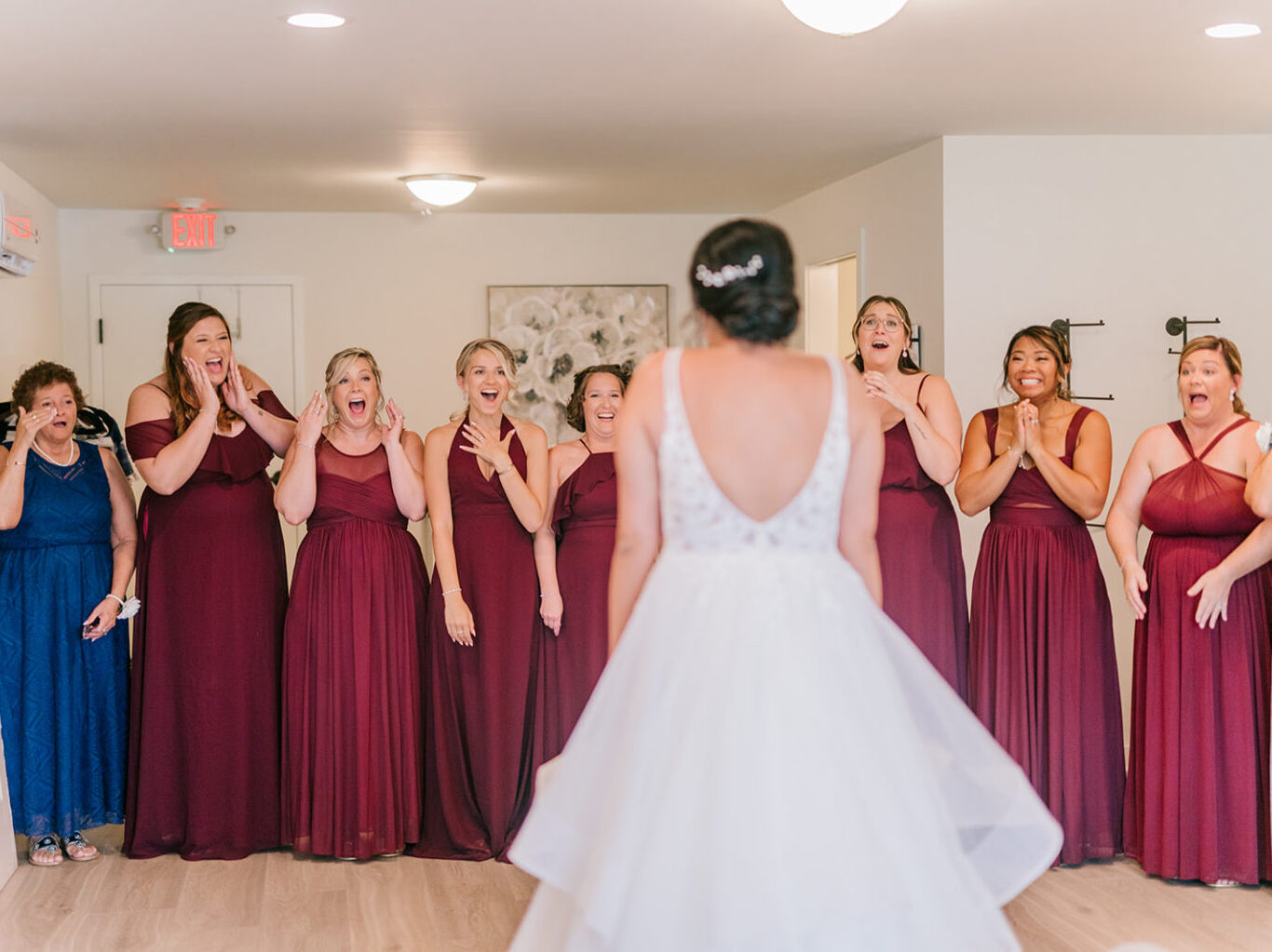 excited bridesmaids and close relatives and friends seeing bride in wedding gown