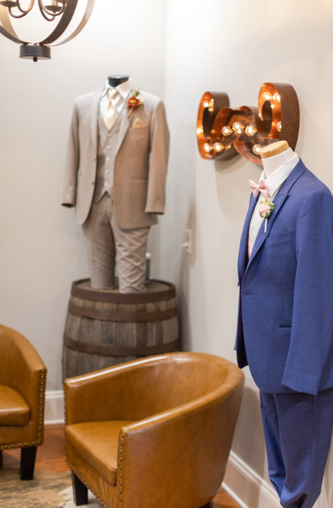 beige and blue tux set up on mannequins in seating area