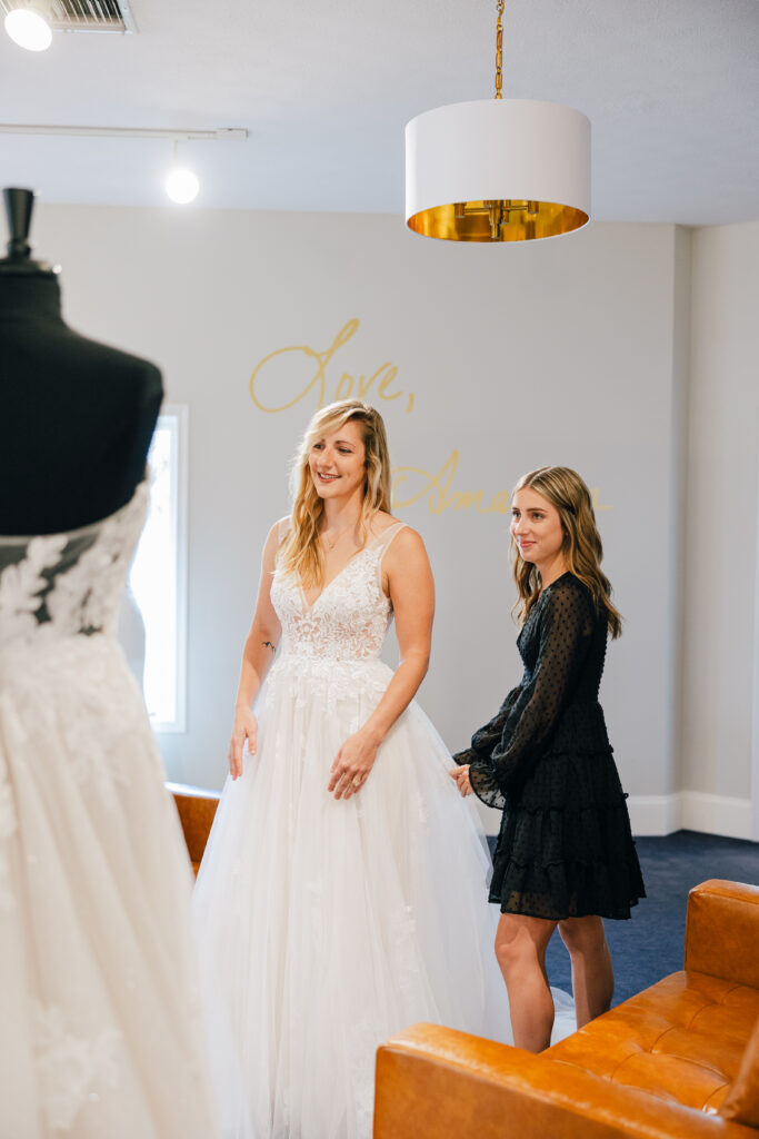 bride to be trying on bridal dress with stylist watching on