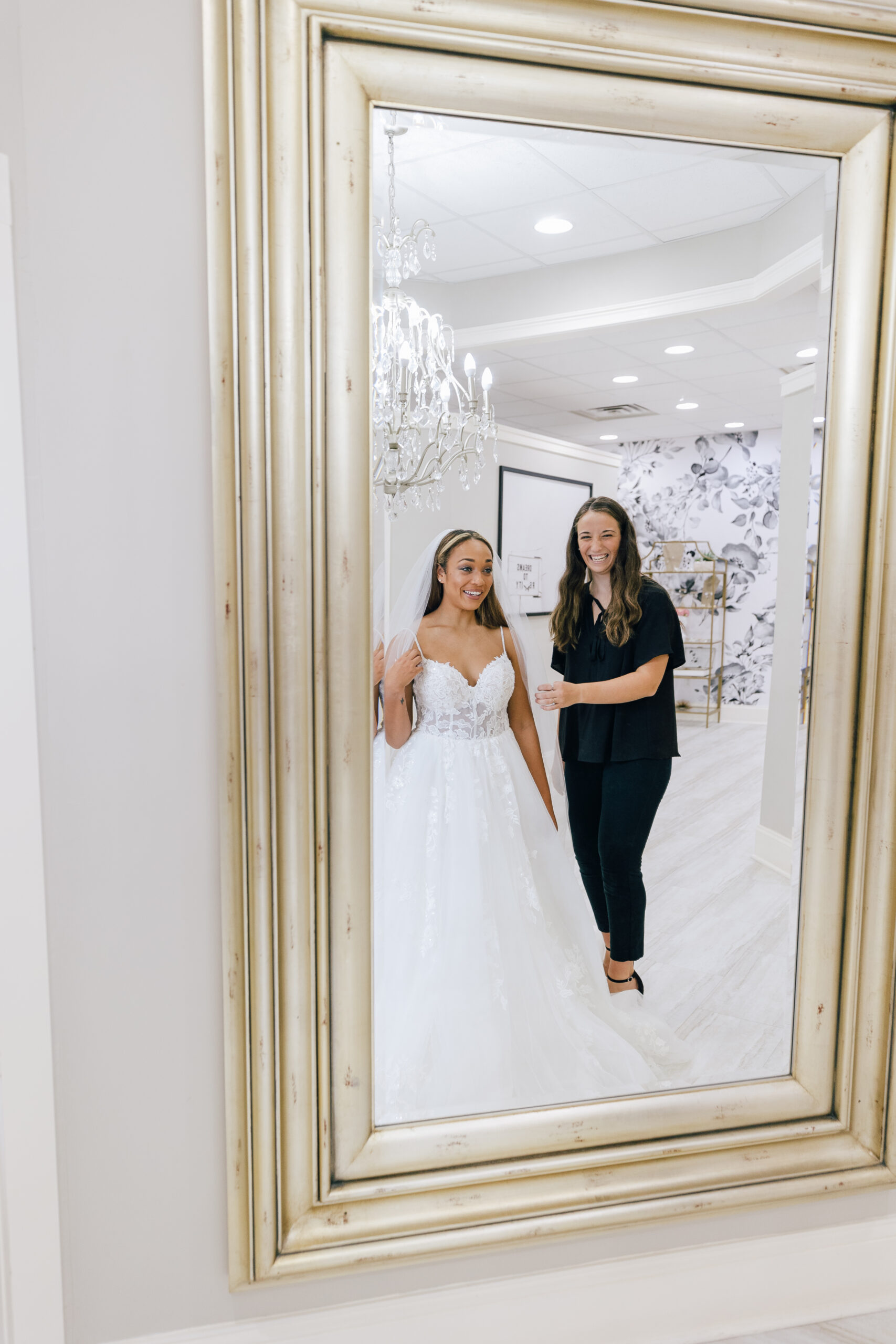happy bride and bridal stylist in mirror