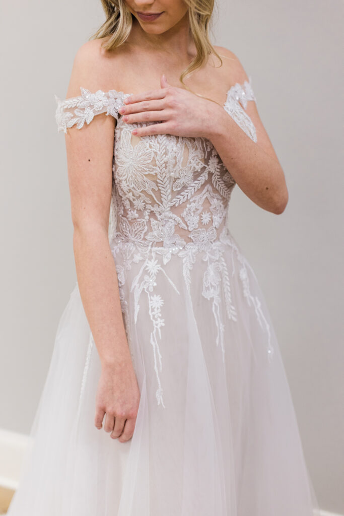 top of off the shoulder style wedding gown with lace cascading into tulle skirt