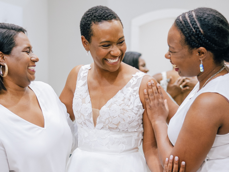 beautiful bride in a wedding dress smiling with her mom and sister by her side