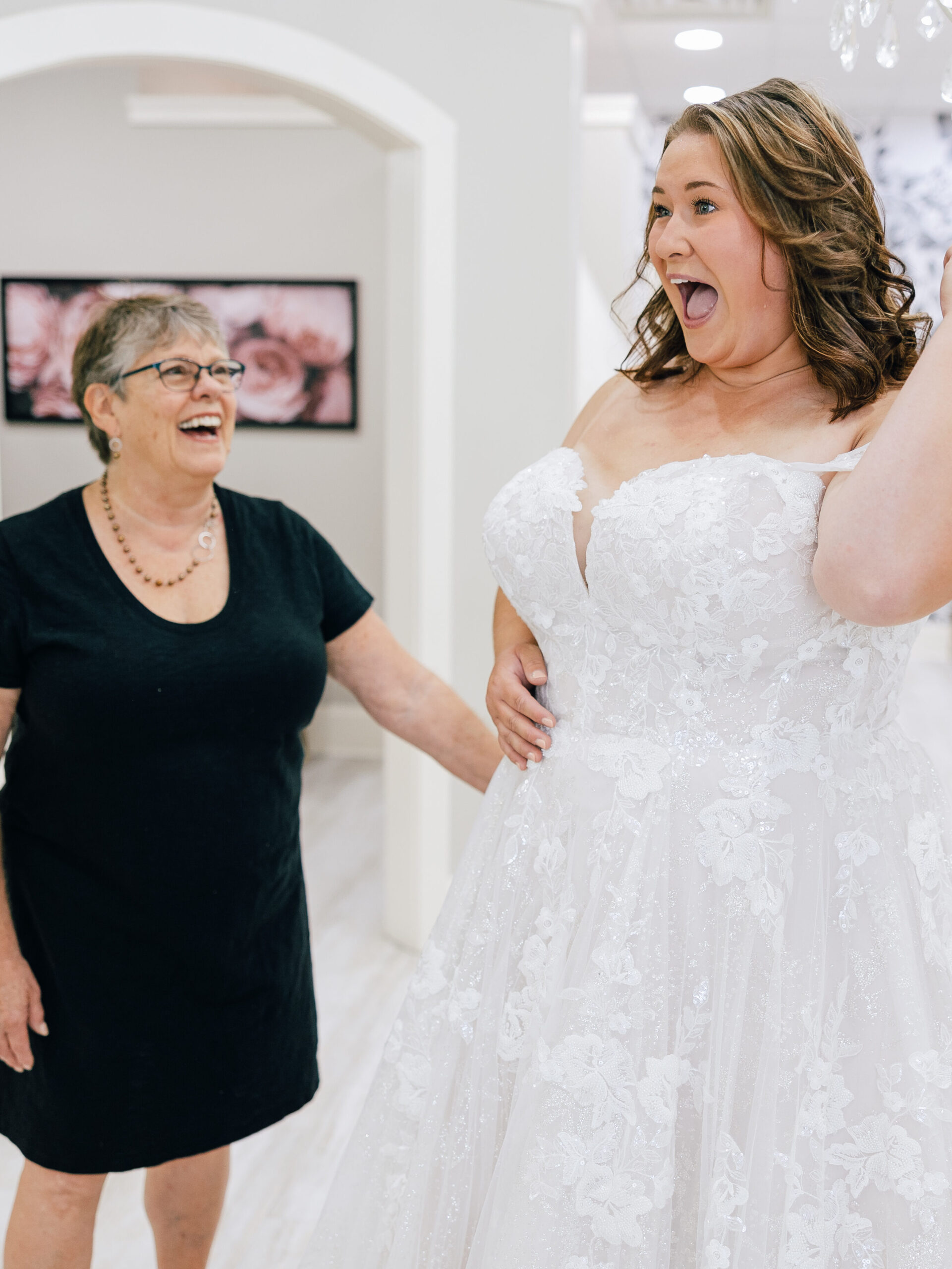 bride standing with her stylist smiling in her wedding dress