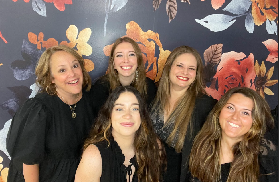 roanokes 5 bridal stylists standing in front of a navy floral wall