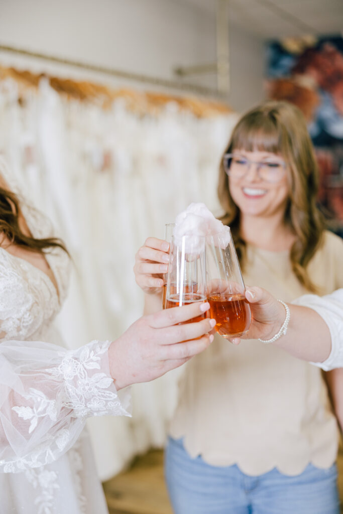 multiple women clinking glasses together as a bride finds her dream wedding dress at Amanda's Touch