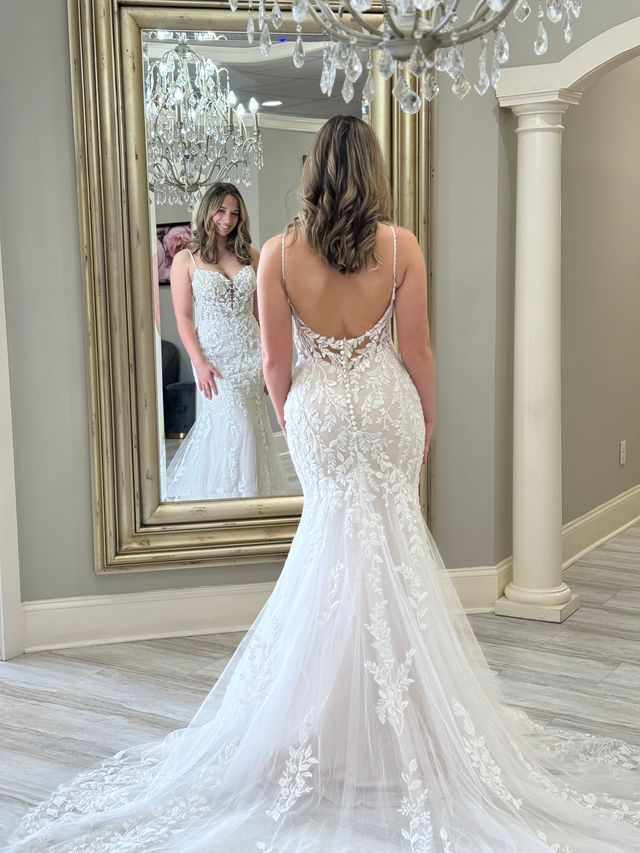 bride standing in front of a mirror admiring her fit-and-flare wedding gown