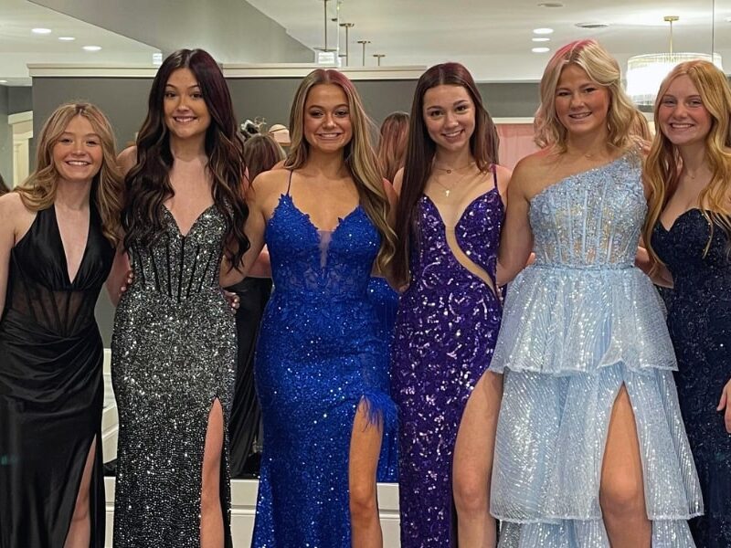 A group of 5 high school girls posing in prom dresses at Amanda's Touch