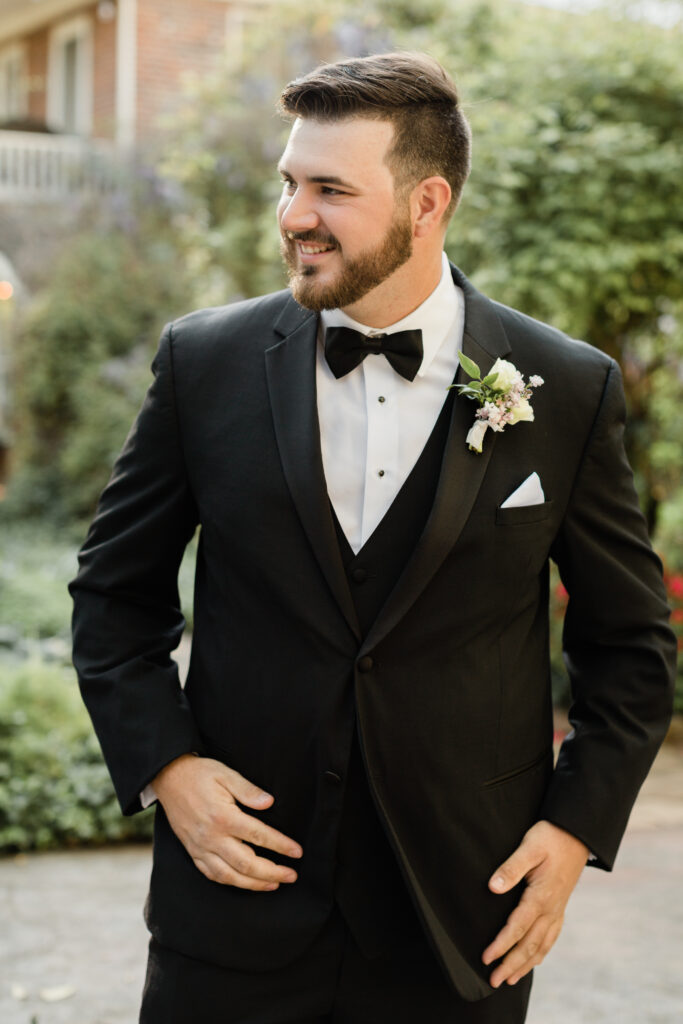 A smiling groom in a classic black tuxedo at his wedding