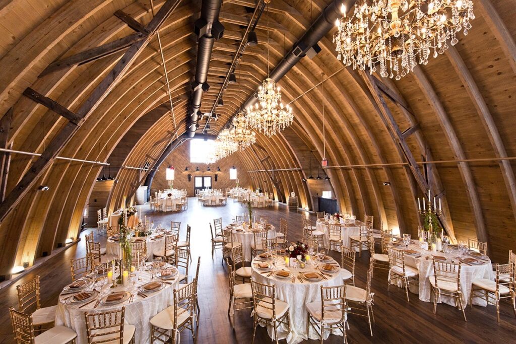 An interior shot of the massive Sweeney Barn, a wedding venue in Virginia with chandeliers hanging from the barn's ceiling.