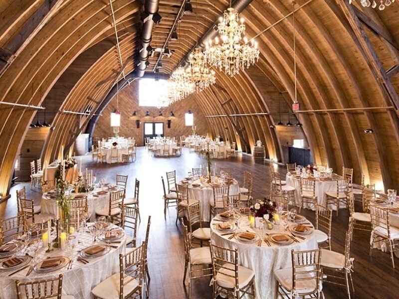 An interior shot of the massive Sweeney Barn, a wedding venue in Virginia with chandeliers hanging from the barn's ceiling.