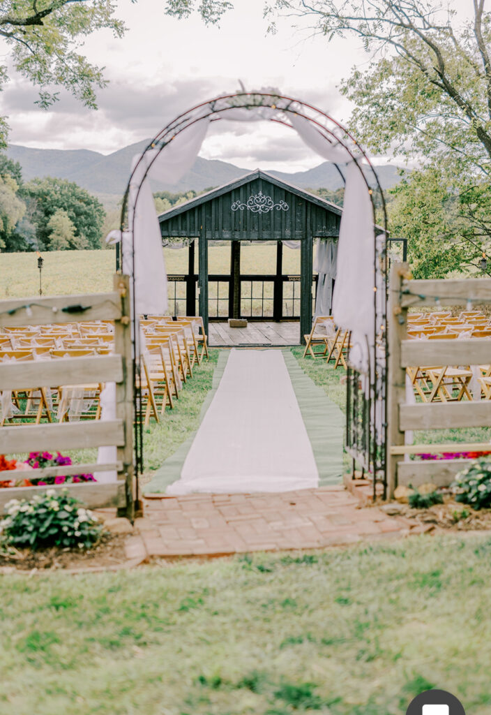 Elegant wedding venue setup with a floral arch overlooking mountainous landscape.