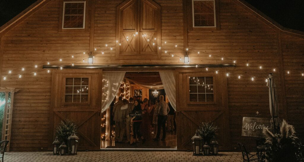 Nighttime view of a barn wedding venue illuminated with string lights.