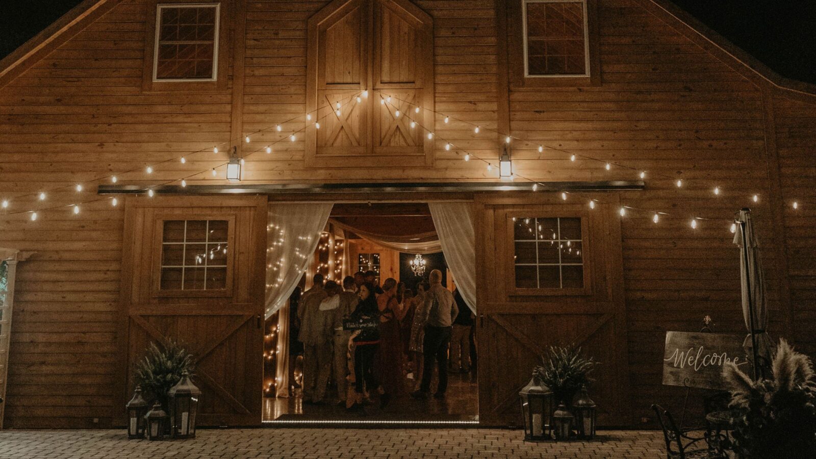 Nighttime view of a barn wedding venue illuminated with string lights.