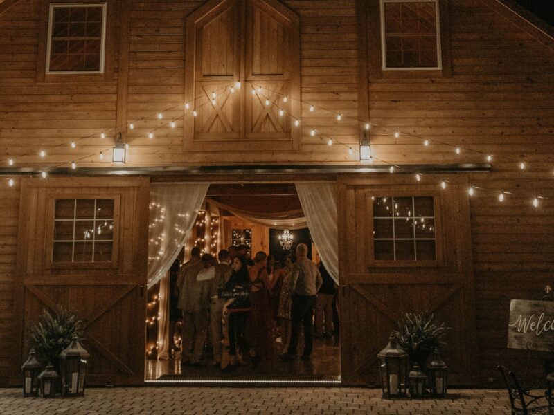 Nighttime view of a barn wedding venue illuminated with string lights.