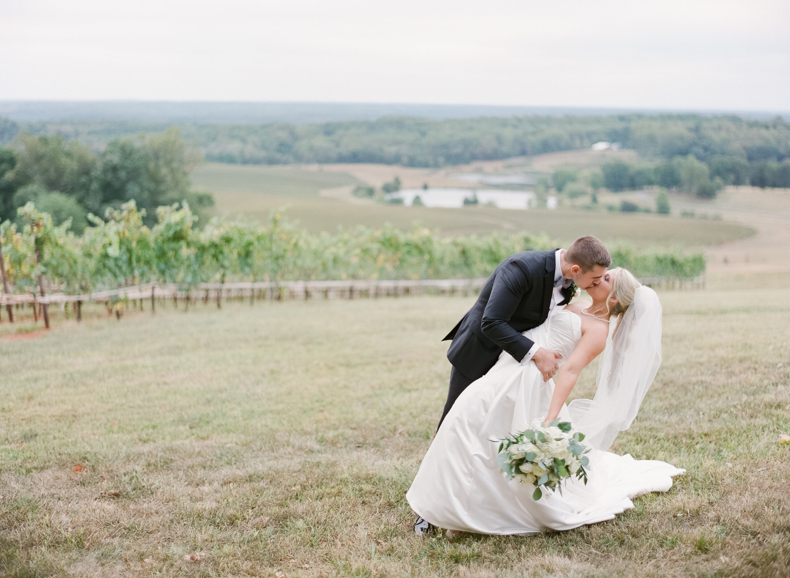 Groom dipping bride back for kiss in a Virginia vineyard wedding venue.