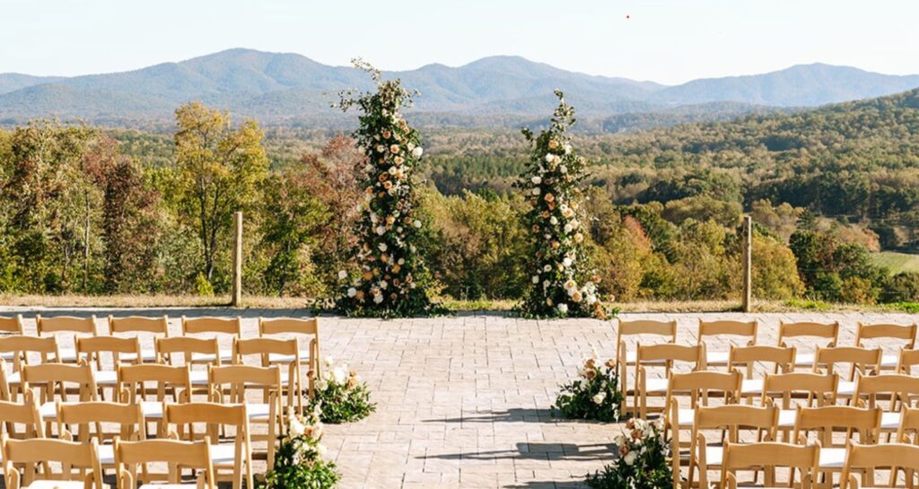 A beautiful wedding ceremony site with tall floral arches and expansive mountain vistas under a clear blue sky.