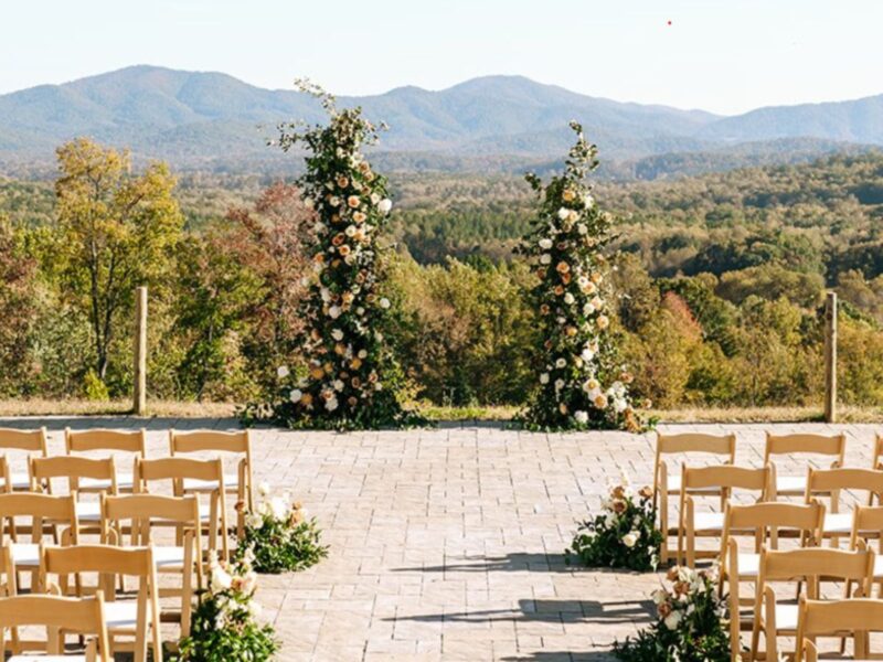 A beautiful wedding ceremony site with tall floral arches and expansive mountain vistas under a clear blue sky.