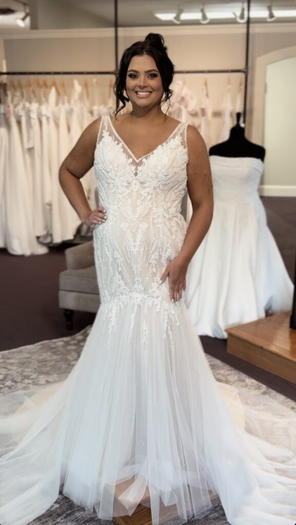 A lace mermaid wedding dress is being fitted on a charming woman during a bridal fitting session.